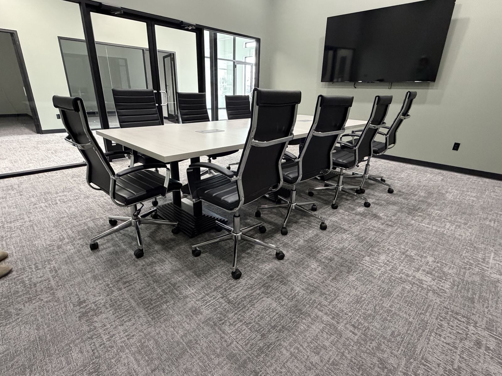 Avenue 118 conference room with seating for nine and a wall-mounted display
